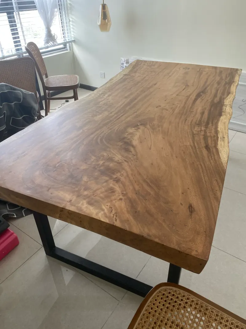 Solid wood slab dining table with natural edge detail and black metal legs